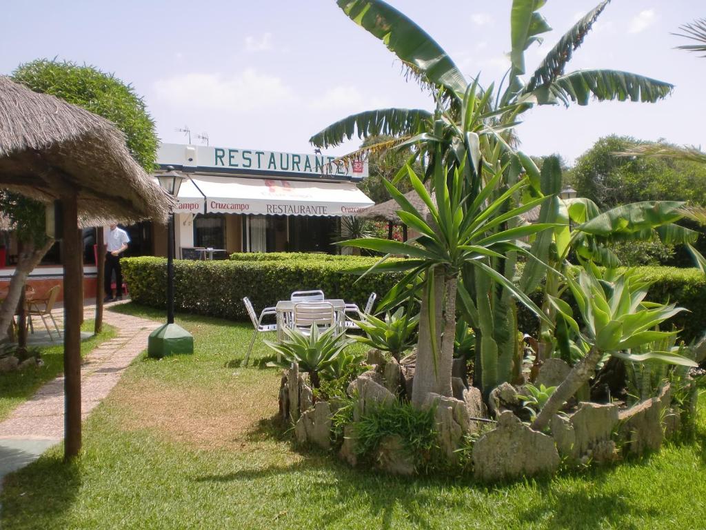 a garden in front of a restaurant with a palm tree at Hostal Restaurante La Ilusion in El Palmar