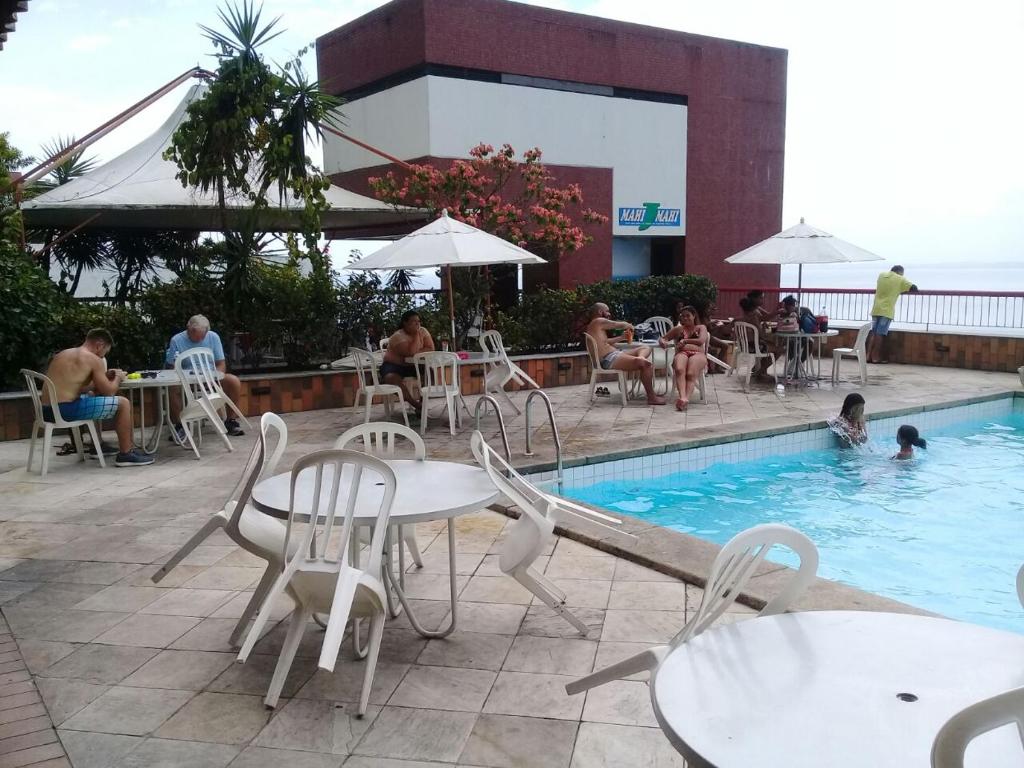 una piscina con mesas y sillas y gente sentada en el agua en Apart Hotel Sol Vitória Marina, en Salvador