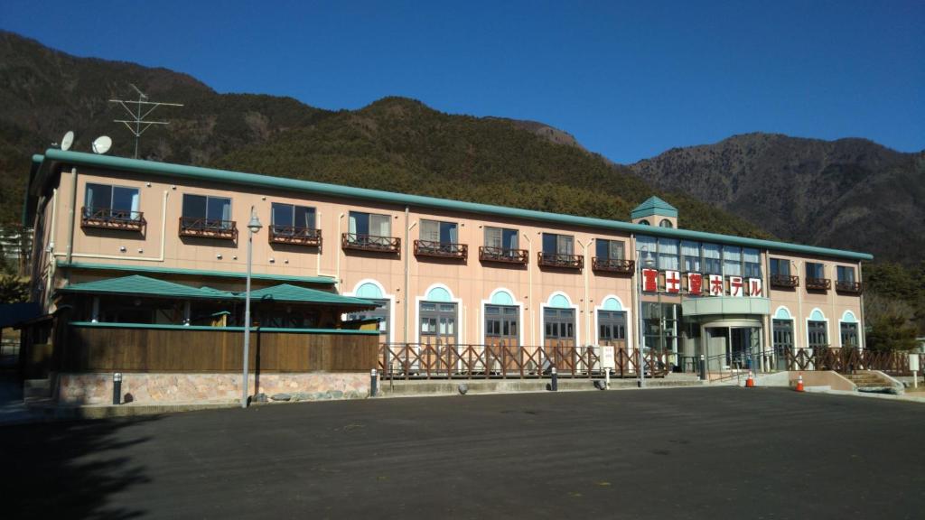 un grand bâtiment avec des montagnes en arrière-plan dans l'établissement Fujibou Hotel, à Fujikawaguchiko