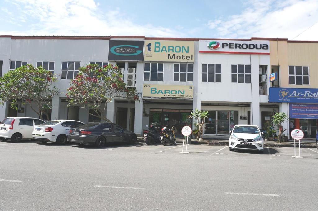 a large white building with cars parked in a parking lot at 1 Baron Motel in Kuah