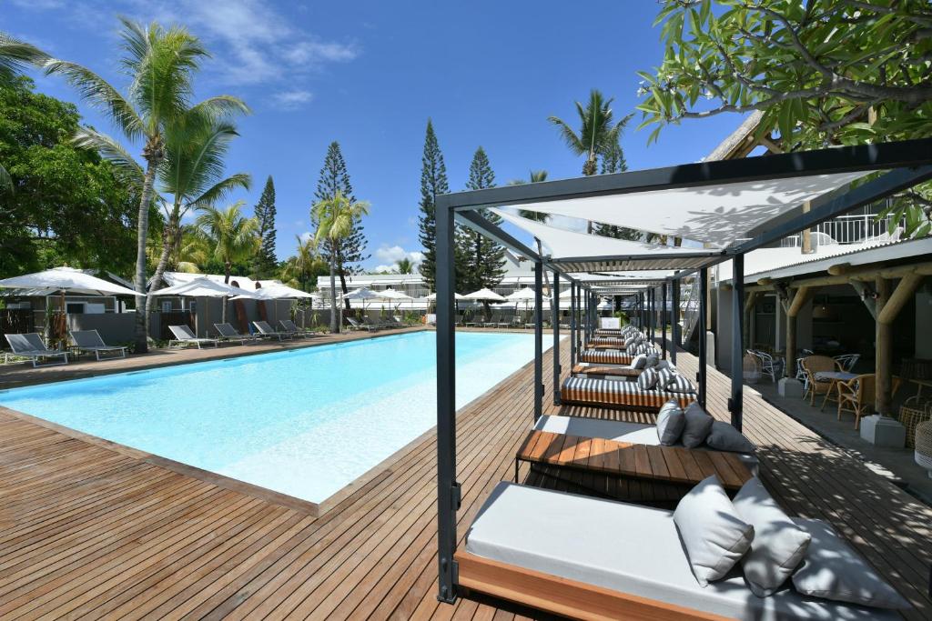 uma piscina com cadeiras e guarda-sóis ao lado de um resort em Veranda Tamarin Hotel & Spa em Tamarin