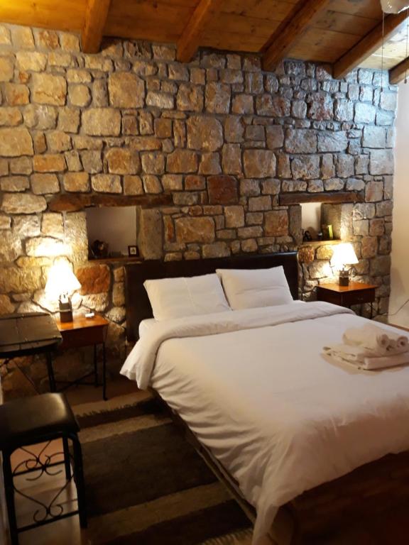 ein Schlafzimmer mit einem großen Bett in einer Steinmauer in der Unterkunft Niriides in Galaxidi