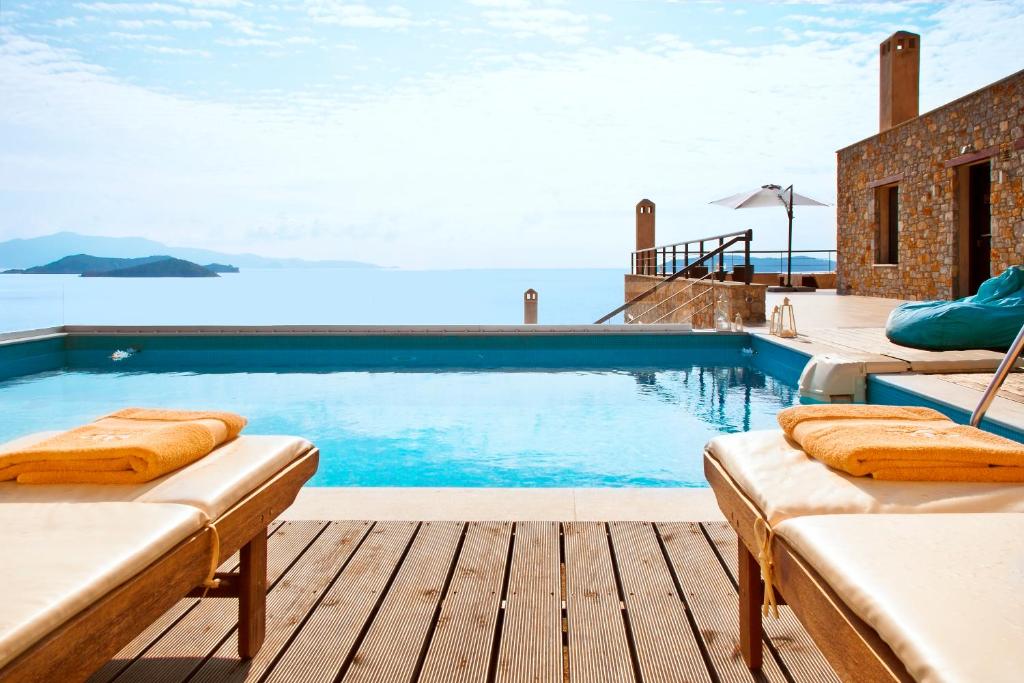 a swimming pool with two chaise lounges on a wooden deck at Golden King Villas in Vassilias