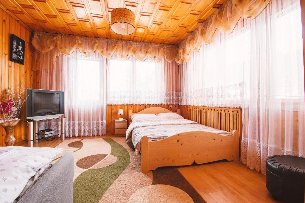 a bedroom with two beds and a television and curtains at Dom na Podhalańskiej in Groń