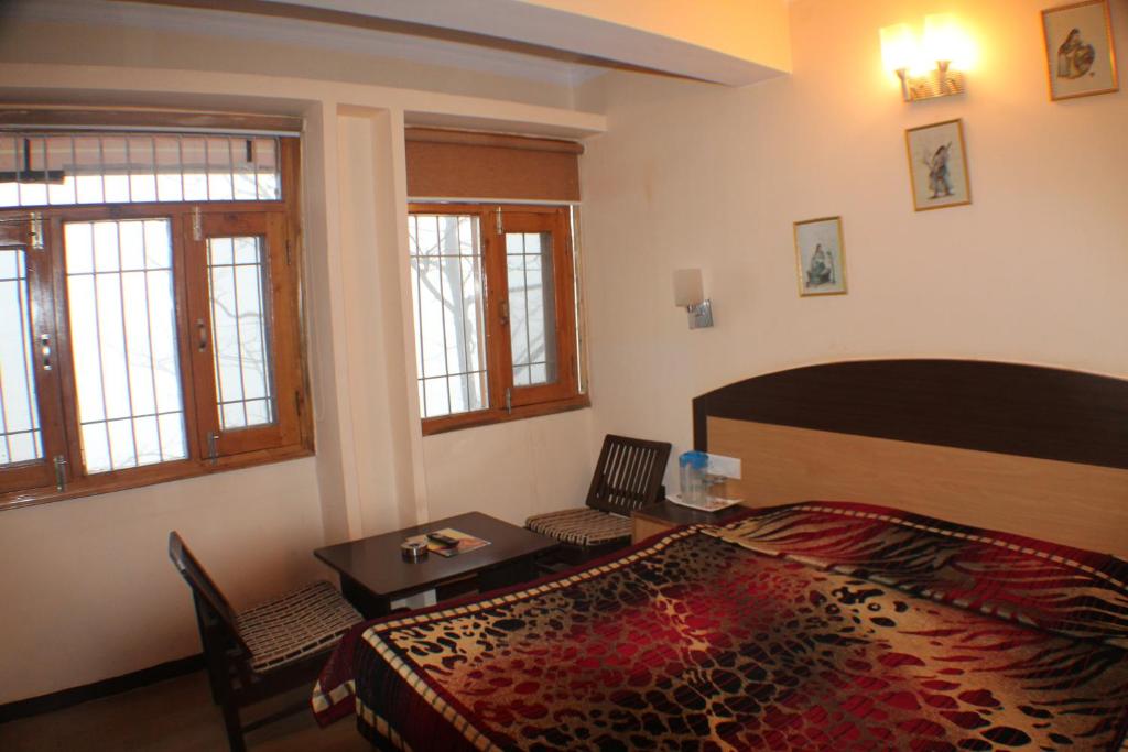 a bedroom with a bed and a table and chairs at Hotel Prestige in Shimla