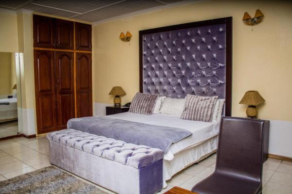 a bedroom with a large bed with a large headboard at Rugems Executive Lodge in Lusaka