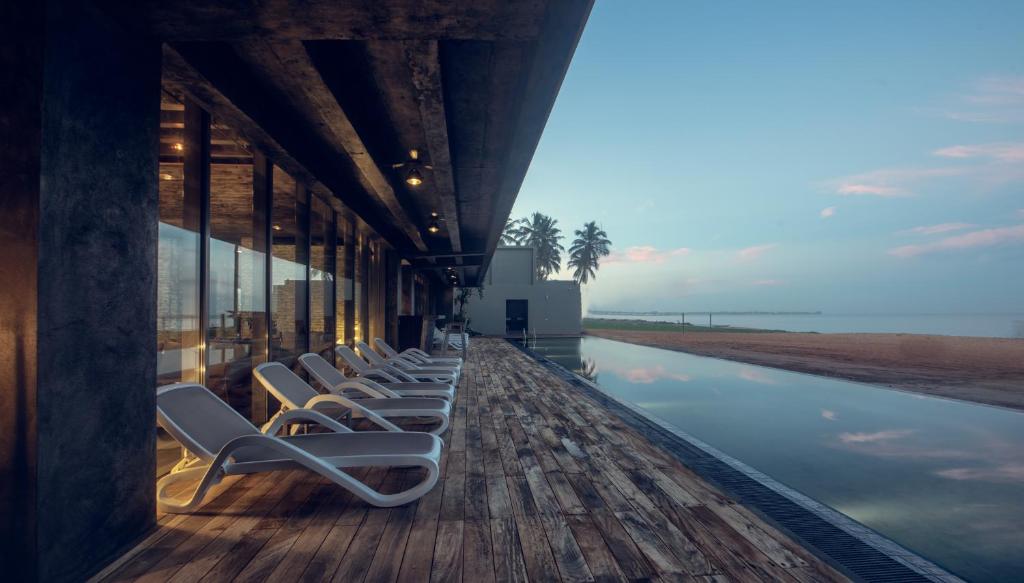 a row of wooden deck chairs sitting on top of a pier at Pledge Scape in Negombo