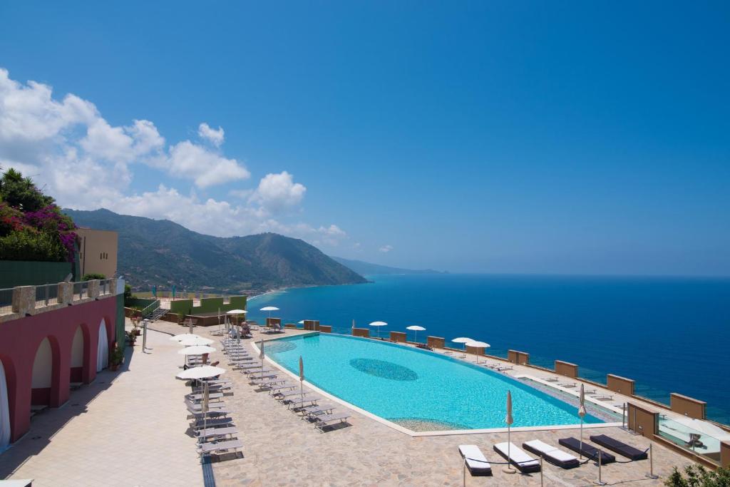 a swimming pool with chairs and a view of the ocean at GH Avalon Sikani in Gioiosa Marea