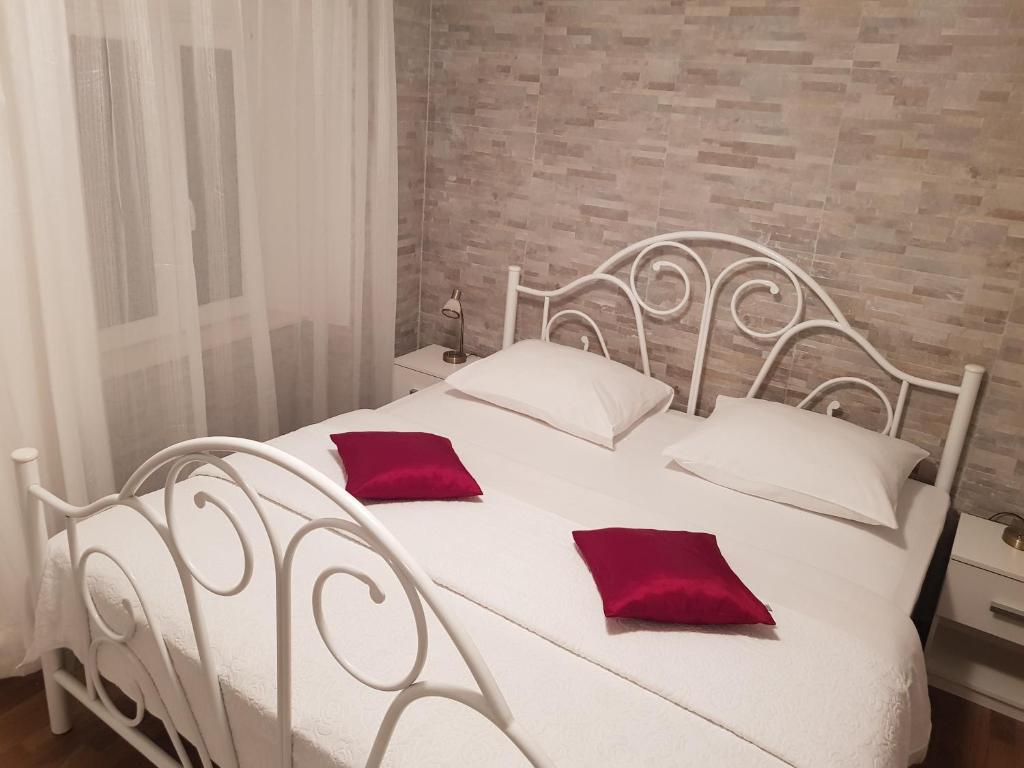 a white bed with two red pillows on it at Apartments Minerva in Dubrovnik