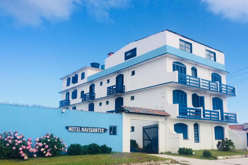 a large white building with blue trim at Hotel Mar Navegantes in Pinhal