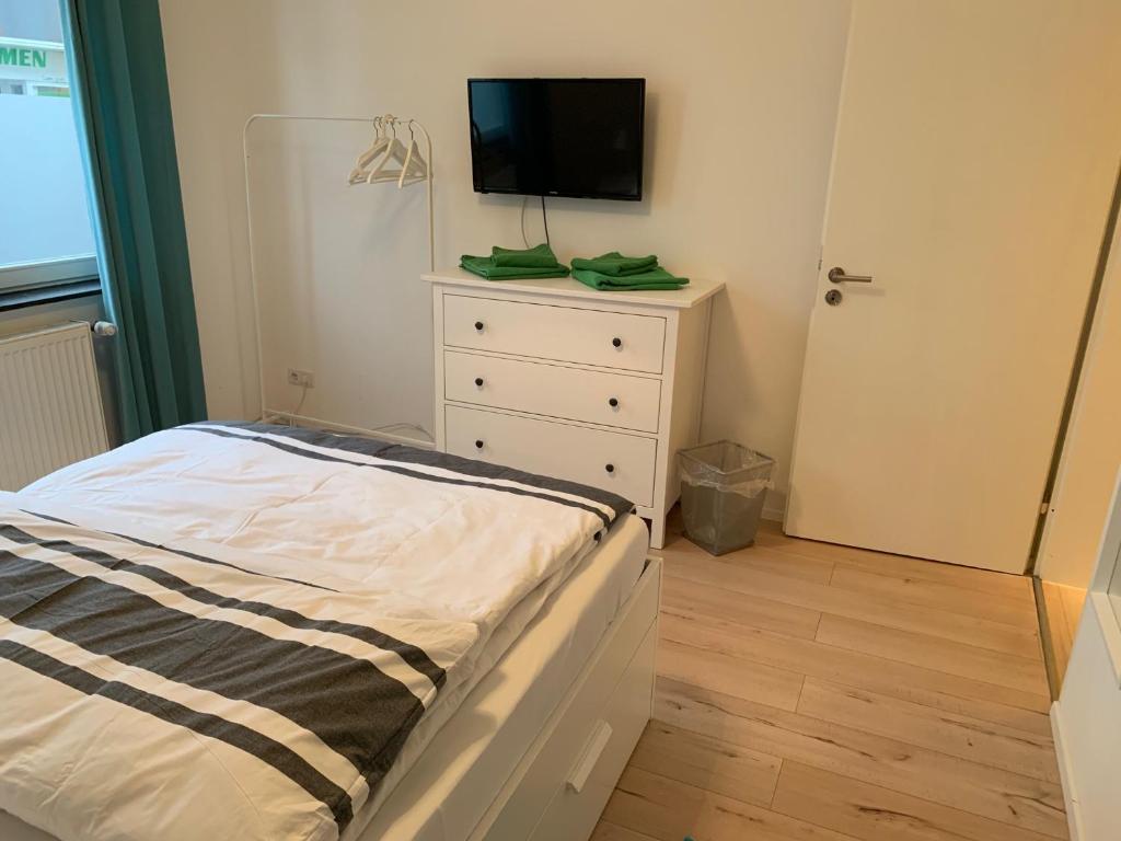 - une chambre avec un lit et une télévision sur une commode dans l'établissement 5min City Zentral - Wohnen am Werdersee Neustadt, à Brême