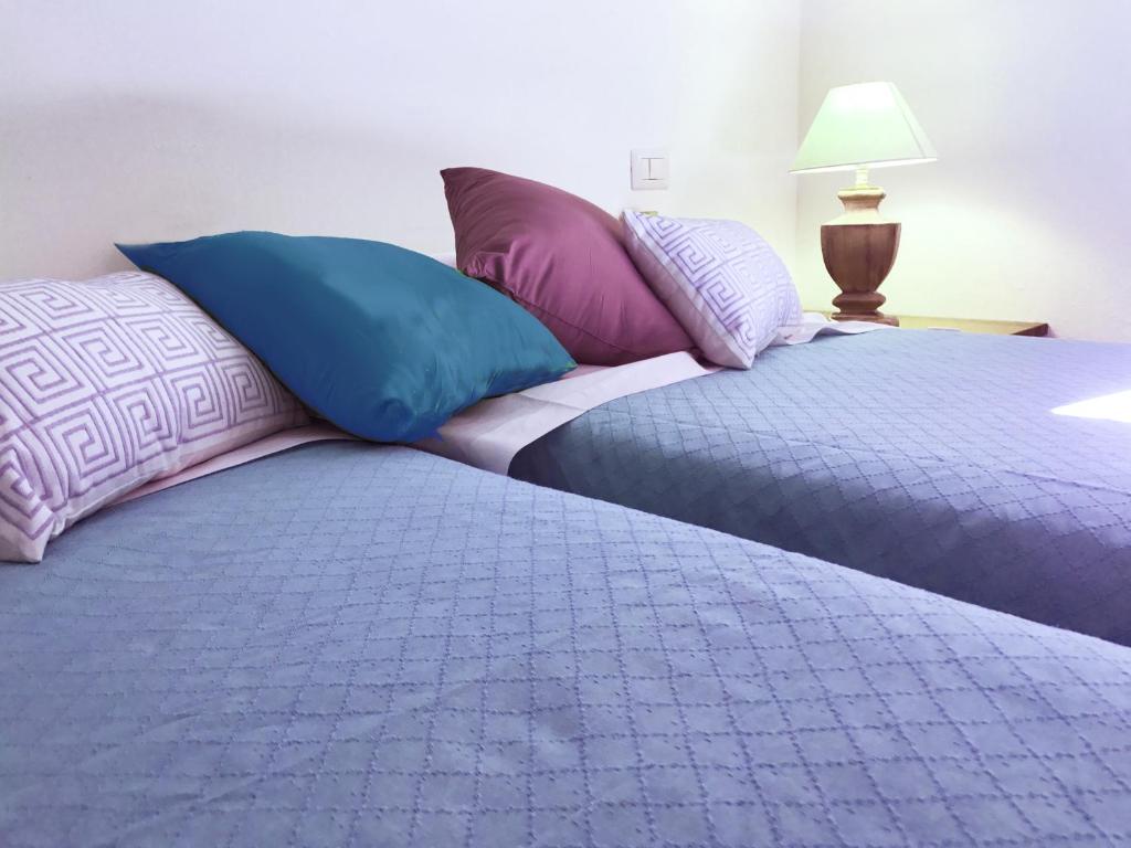 two beds with colorful pillows sitting next to each other at Sa Tirìa in Chia