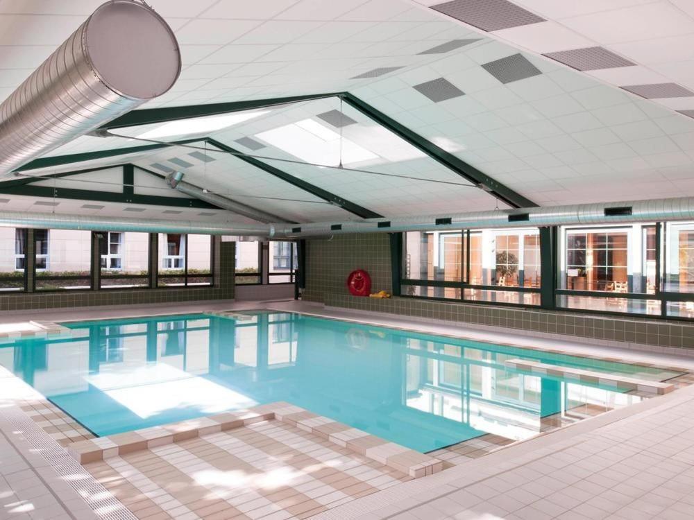 a large swimming pool in a building with windows at LA SUITE ENCHANTÉE Disneyland Paris in Serris