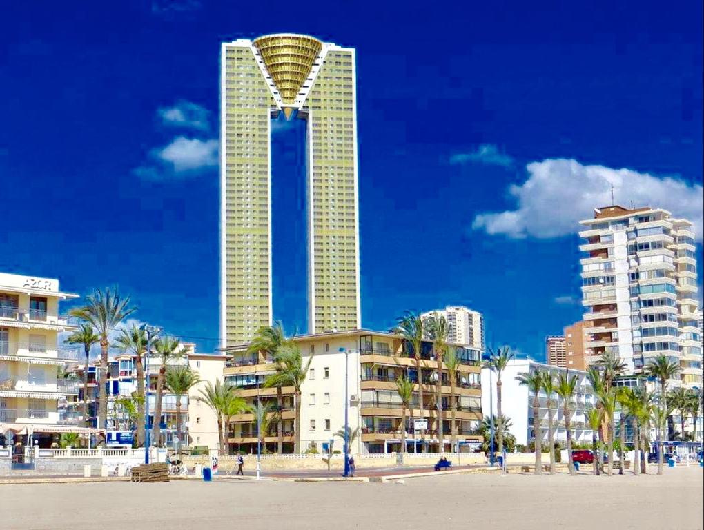 ベニドルムにあるNeptuno on the Beachのヤシの木や建物が立ち並ぶ海辺の高層ビル