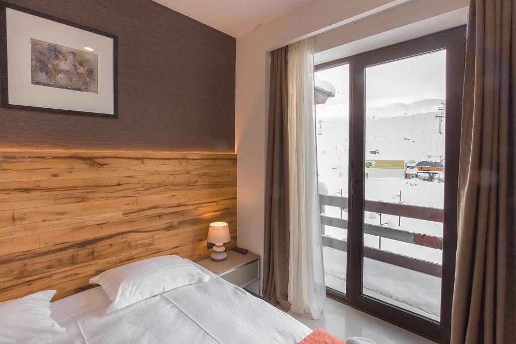 a bedroom with a bed and a window with a view of the beach at Zen Apartments Gudauri in Gudauri