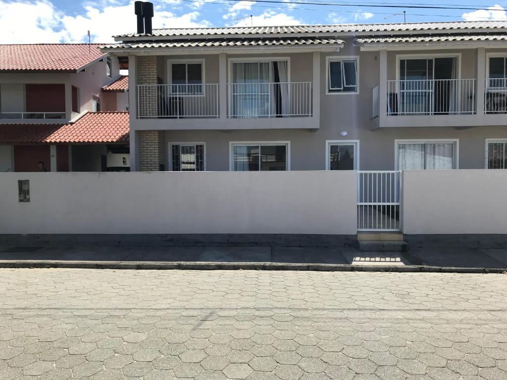 a white fence in front of a house at Apartamento Sunset 101 in Palhoça