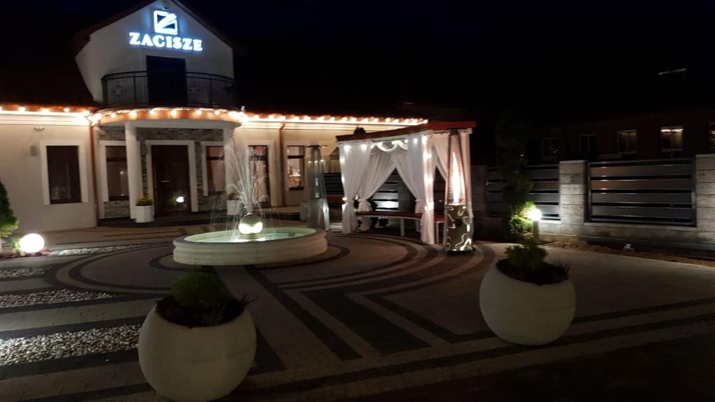 a building with a fountain in front of it at night at Zacisze in Sokółka