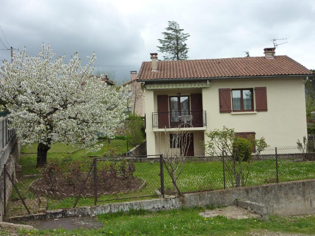 a house with a flowering tree in front of it at Le cerisier in Millau
