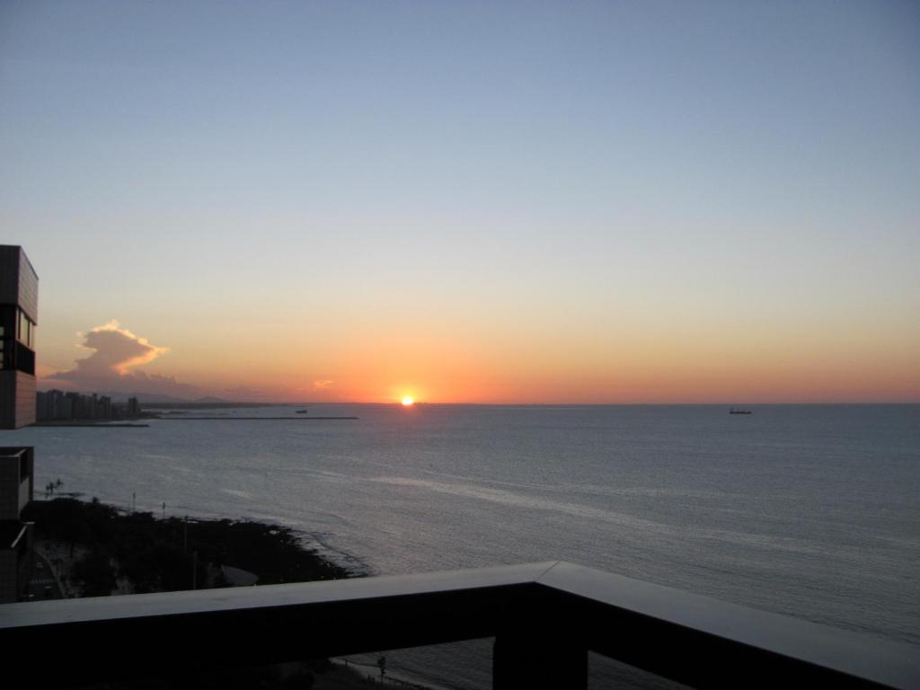 a sunset over the ocean from a balcony at Vip Iracema Flat in Fortaleza