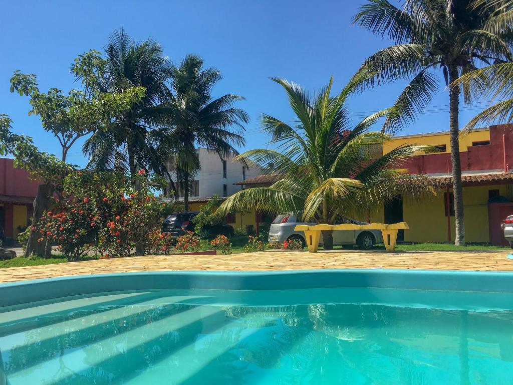 a pool in front of a building with palm trees at Pousada dos Gravatais in Marataizes