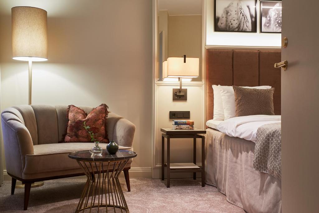 a bedroom with a bed and a chair and a table at Bank Hotel, a Member of Small Luxury Hotels in Stockholm