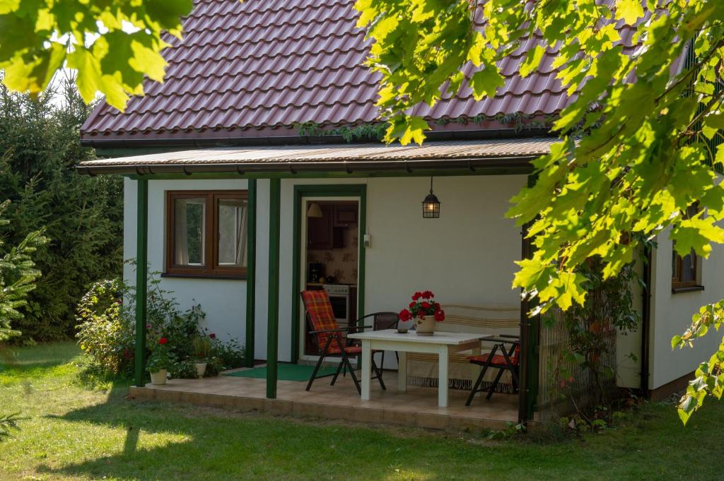 a small white house with a table and chairs at Rydzewo Zacisze Domek Całoroczny in Rydzewo