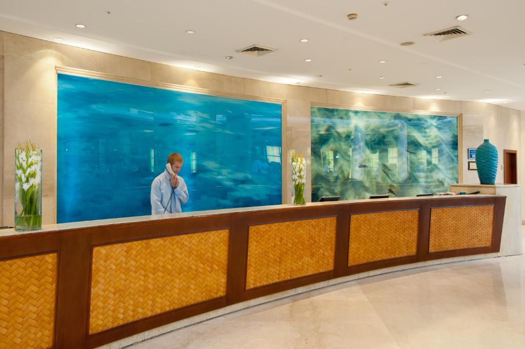 ein Mann steht an einem Tresen in einer Hotellobby in der Unterkunft U Magic Palace in Eilat