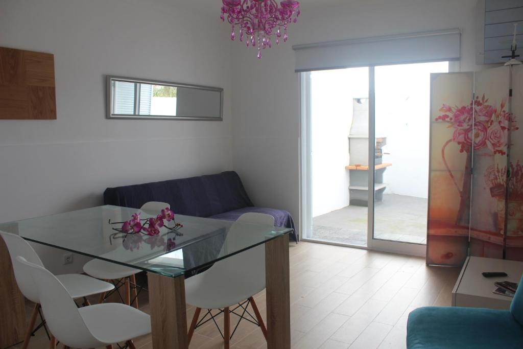 - un salon avec une table en verre et des chaises blanches dans l'établissement Casa da Praceta, à Ponta Delgada