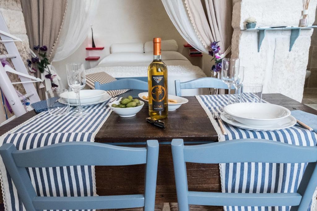 tavolo da pranzo con una bottiglia di vino e sedie di Casa di Amici a Ostuni