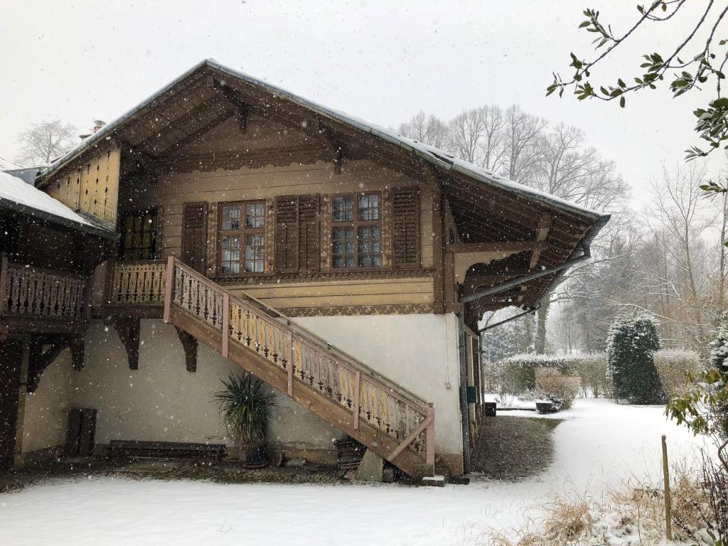 une maison en bois avec un escalier dans la neige dans l'établissement La Datcha du Parc, à Husseren-Wesserling