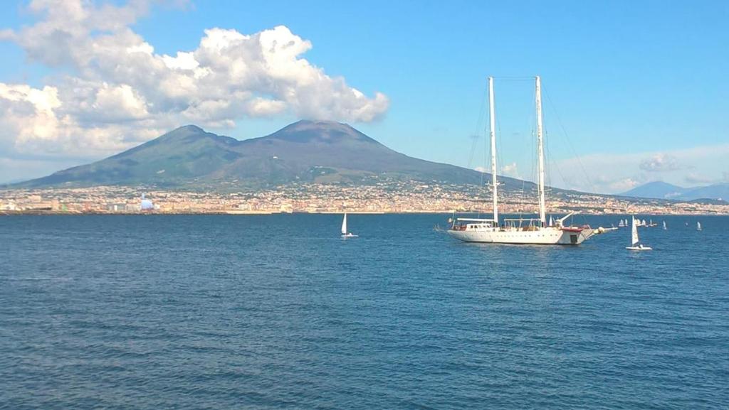 a boat in the water with a mountain in the background at Napoli Storia e Mare in Naples