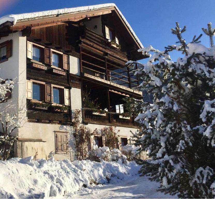 a large wooden building with snow in front of it at Maso Drigo in San Niccolò Comèlico