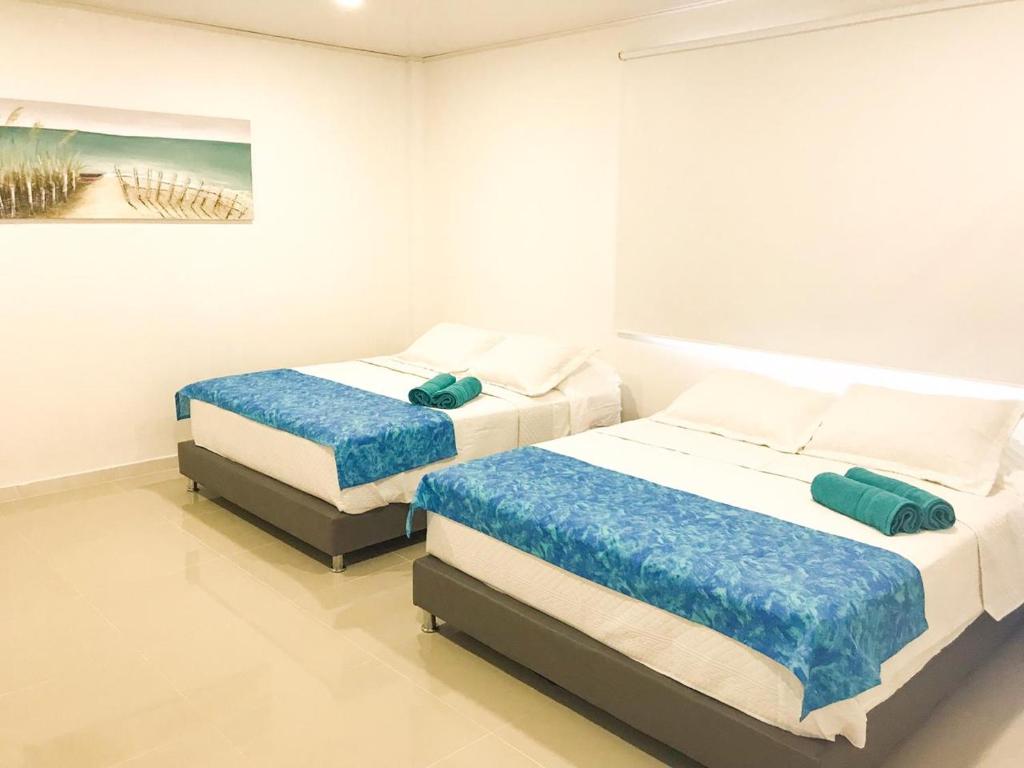two beds in a white bedroom with a painting at Tropical Breeze Aeropuerto in San Andrés