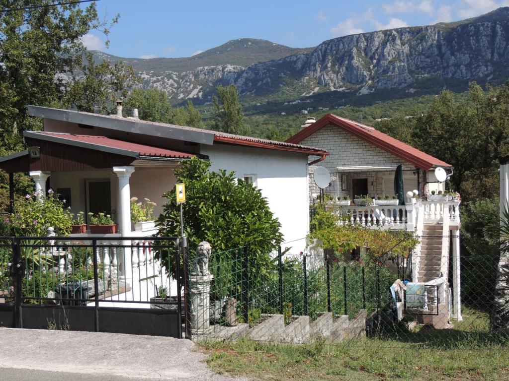 a house with a fence and mountains in the background at Villa Behija Ferienwohnung 2 Crikvenica in Crikvenica