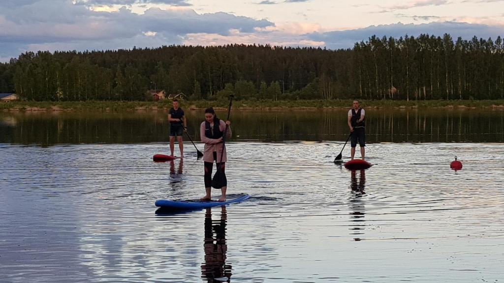 three people are standing on a paddle board on a lake at Pitkämö Canyon Camping Oy in Kurikka