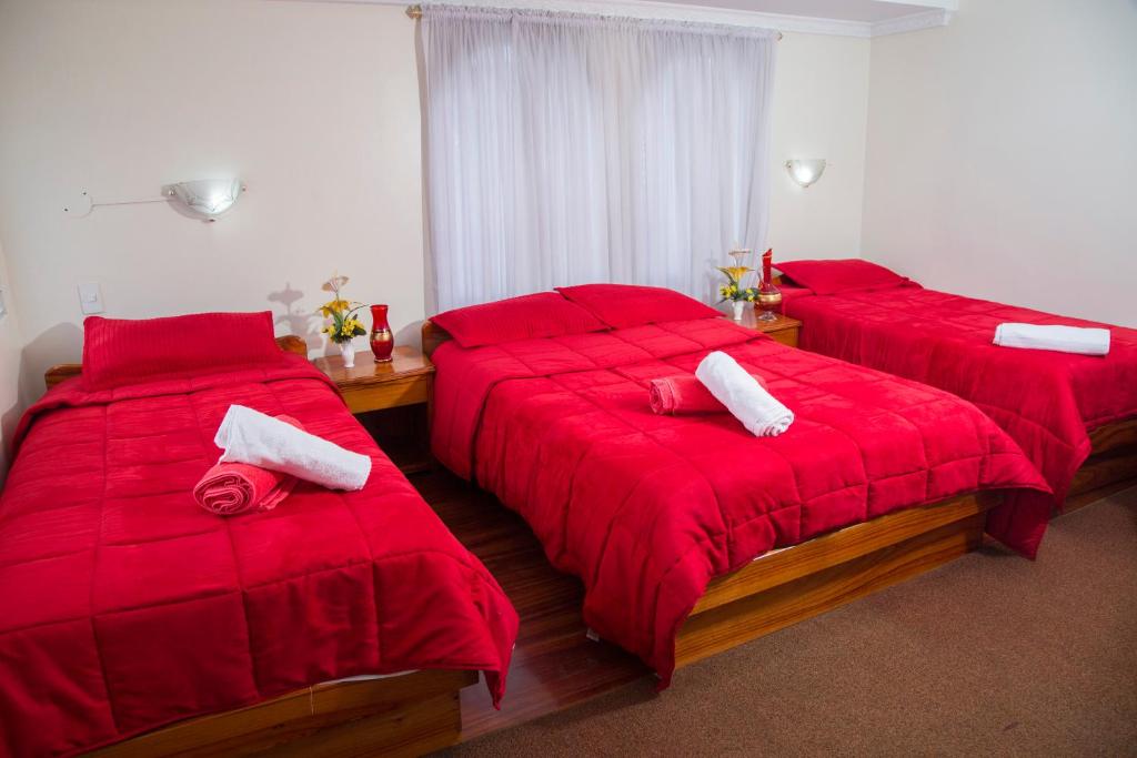 two beds in a room with red comforters at Hotel Plaza del Teatro in Quito