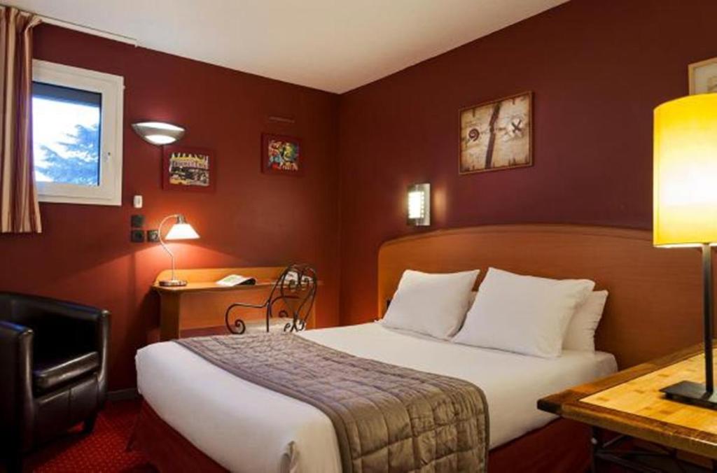 Pokój hotelowy z łóżkiem i biurkiem w obiekcie Sky Hotel Goussainville Charles de Gaulle w mieście Goussainville
