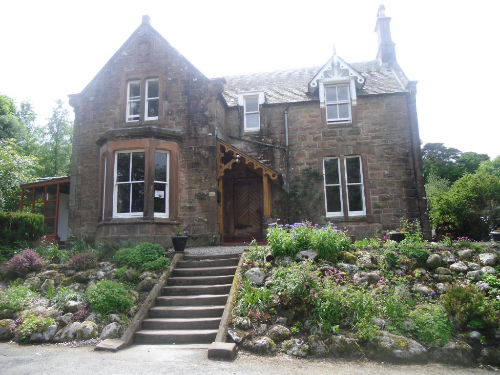 an old stone house with a garden in front of it at Ormidale Hotel in Brodick