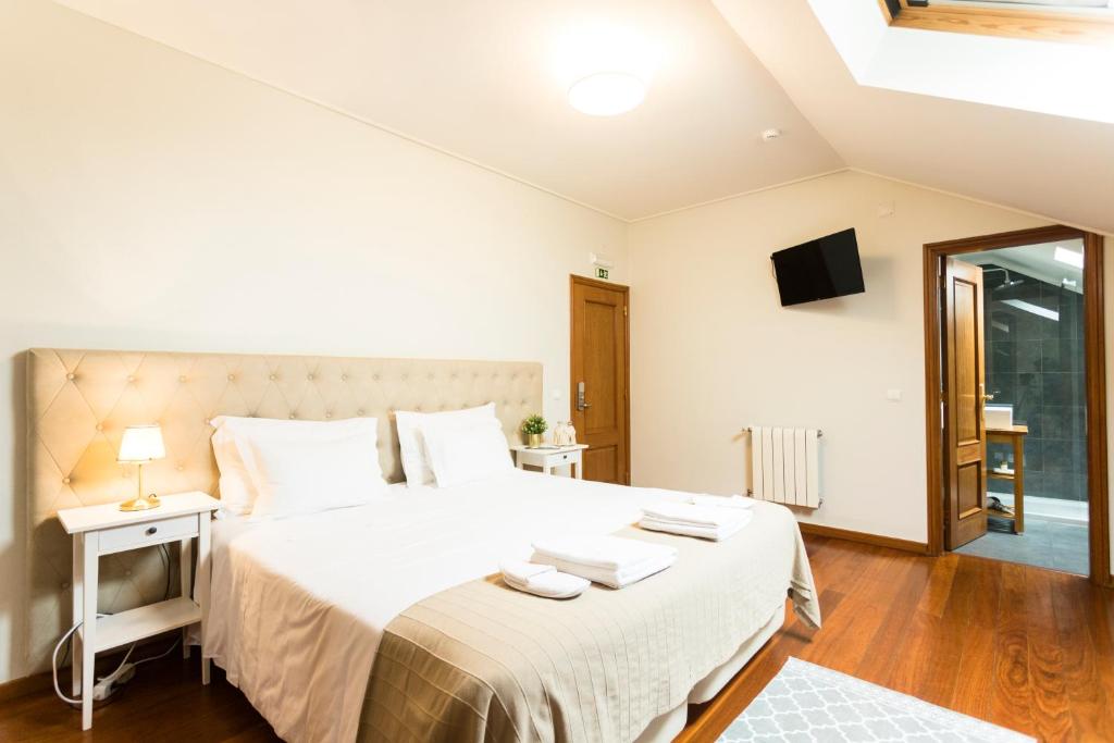a bedroom with a large white bed and a television at Ericeira Soul Guesthouse in Ericeira