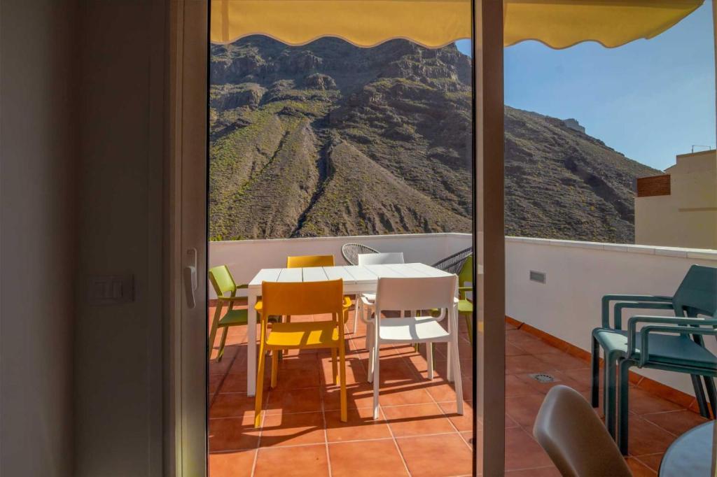 a table and chairs on a balcony with a mountain view at Casa La Alameda,Valle Gran Rey, La Gomera in Valle Gran Rey