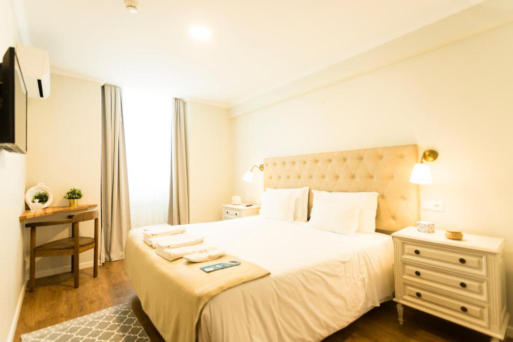 a bedroom with a large white bed and a dresser at Ericeira Soul Guesthouse in Ericeira