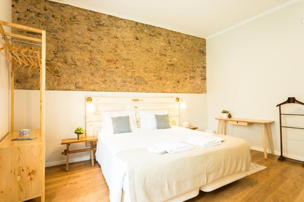 a bedroom with a large white bed and a brick wall at Ericeira Soul Guesthouse in Ericeira
