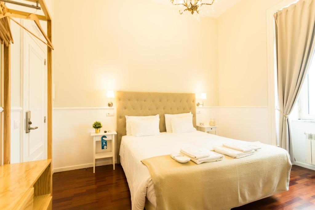 a bedroom with a large white bed with towels on it at Ericeira Soul Guesthouse in Ericeira