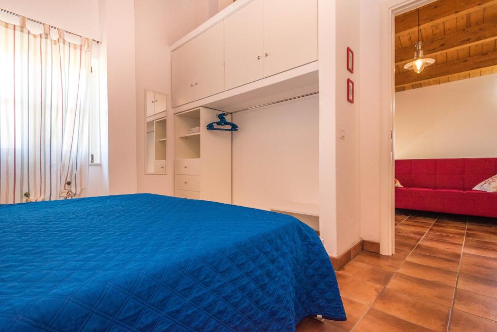 a bedroom with a blue bed and a red couch at Casa del Sale, a 50 m dalla spiaggia in Lascari