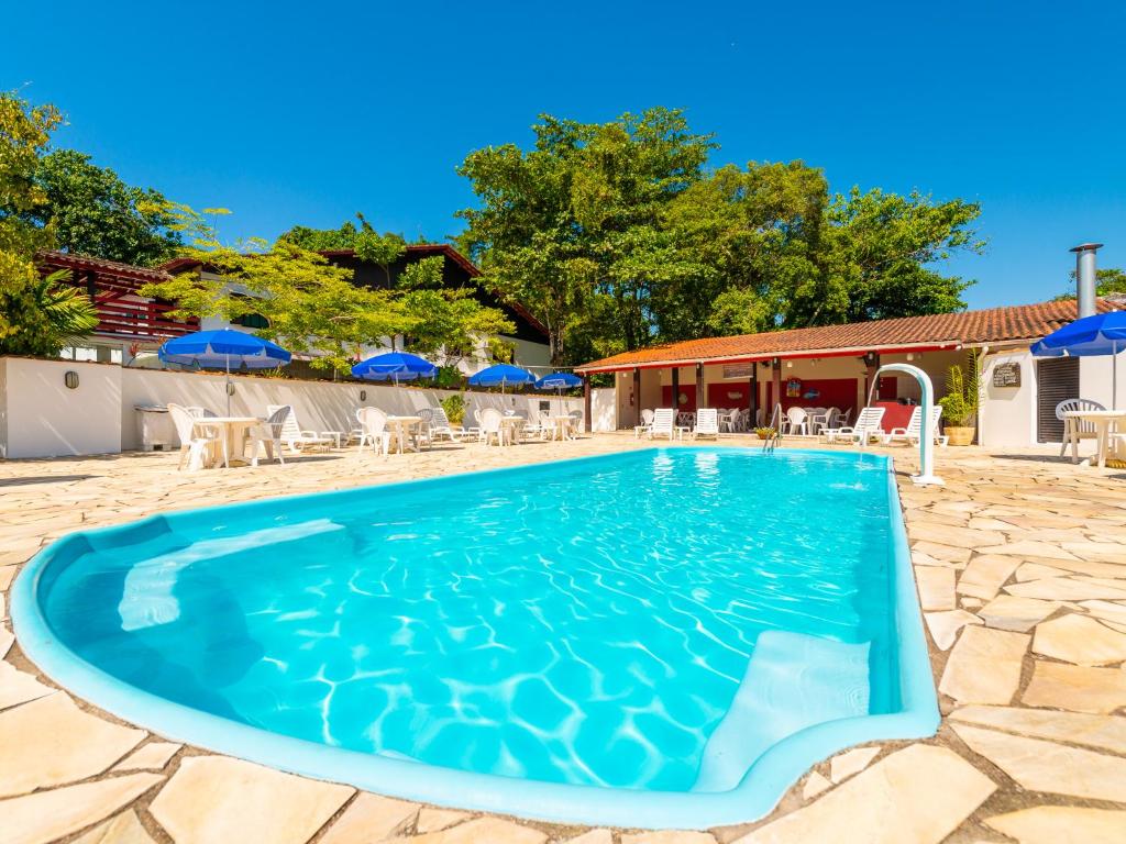 una piscina con sillas y sombrillas en un complejo en Hotel Saveiros, en Ubatuba