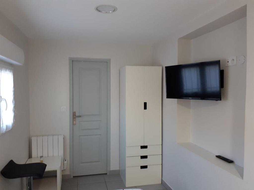 a living room with a white cabinet and a flat screen tv at studio climatisé in Avignon