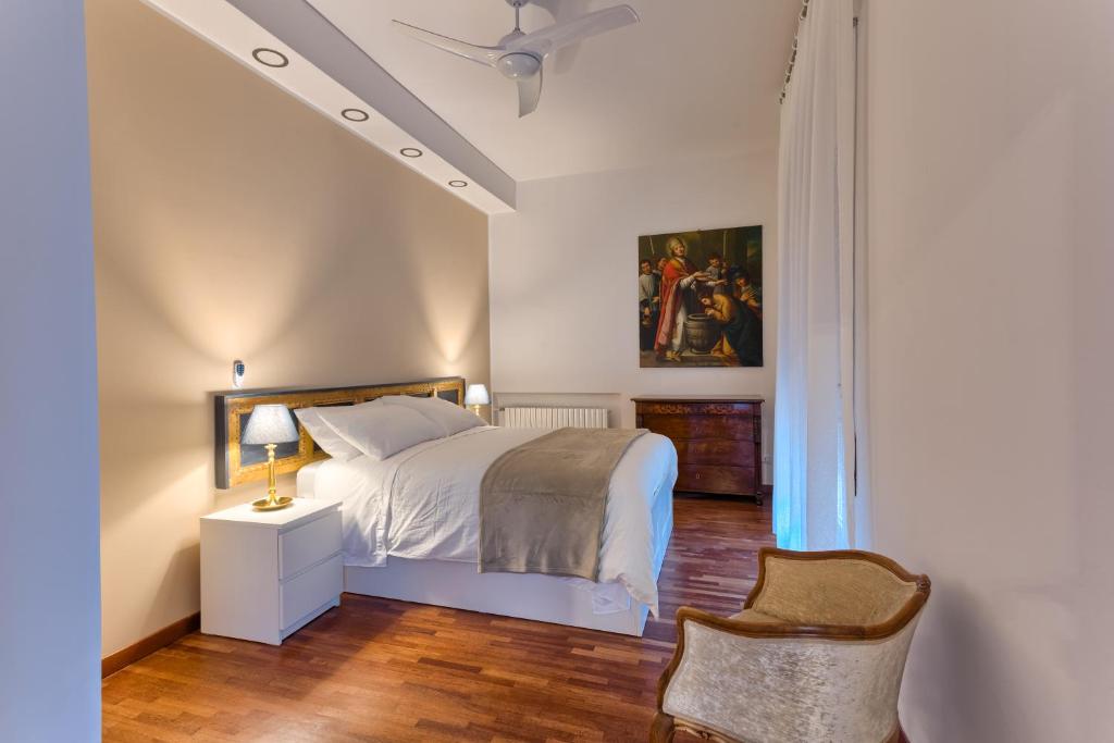 ein Schlafzimmer mit einem weißen Bett und einem Stuhl in der Unterkunft Appartamenti Tommasini in Bologna