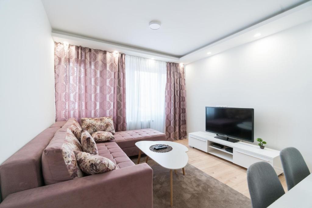 een woonkamer met een bank en een tv bij Apartman Skenderija in Sarajevo
