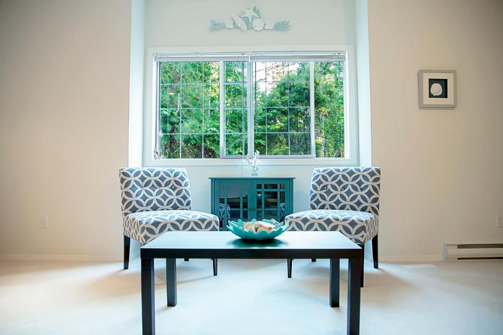 a living room with two chairs and a table and a window at The Inlet Bed & Breakfast in Saanichton