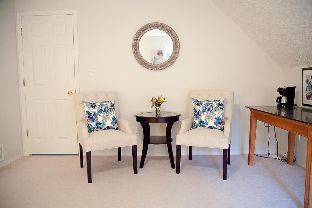 a dining room with two chairs and a table and a mirror at The Inlet Bed & Breakfast in Saanichton